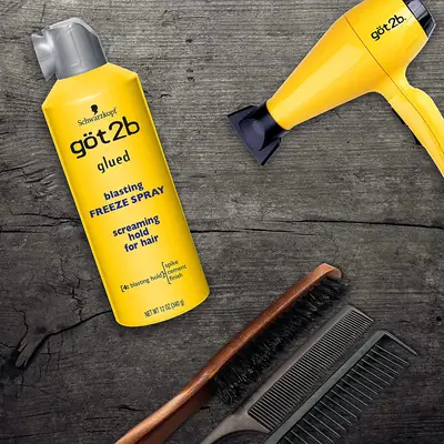 Spray fijador para el cabello junto a un secador y un cepillo